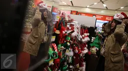 Pengunjung mencoba beberapa pernak-pernik natal yang dijual di Mall Gandaria City, Jakarta, Rabu (9/12/2015). Jelang perayaan hari raya umat Kristen, berbagai pernak-pernik dan hiasan rumah bertema Natal kini mulai marak. (Liputan6.com/Faizal Fanani)