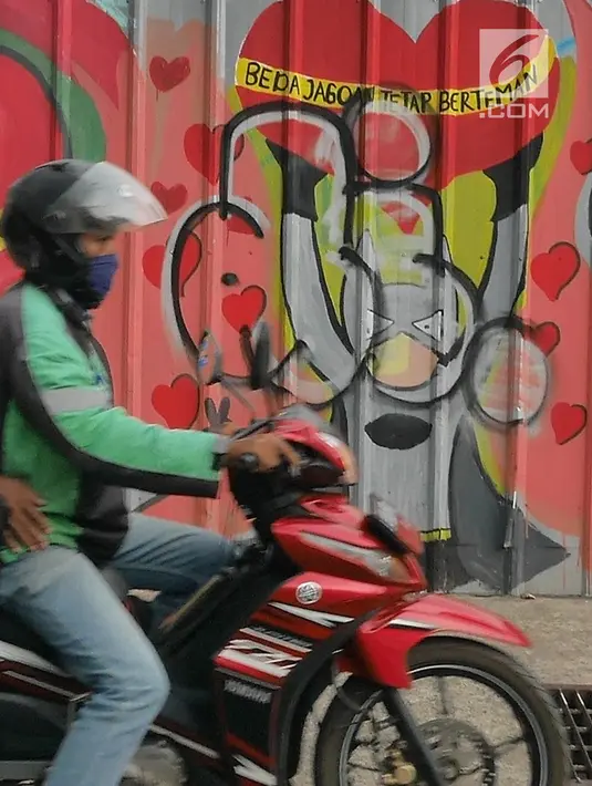 Pengendara melintasi mural yang menghiasi tembok di kawasan Margonda, Depok, Sabtu (16/2). Gambar mural memiliki pesan agar masyarakat tetap damai dan berteman meski berbeda dalam memilih calon presiden dalam Pilpres 2019. (Liputan6.com/Herman Zakharia)