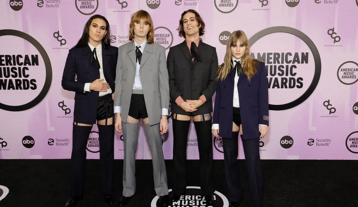 Maneskin tampil menawan dalam balutan busana dari Gucci. Keempatnya tampil seragam dengan blazer dalam palet warna yang terkoordinasi; biru navy, abu-abu, hitam, dan ungu tua. Lengkap dengan kemeja sebagai innerwear, diberi sentuhan pita hitam yang sangat khas Gucci. Foto: Vogue.