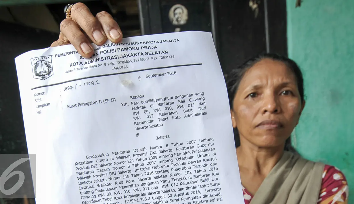 Warga Bukit Duri menunjukan Surat Peringatan (SP) 2 yang dilayangkan oleh Pemprov DKI, Jakarta, Rabu (7/9). Pemprov DKI Jakarta layangkan SP2 untuk warga Dukit Duri, Tebet terkait normalisasi kali Ciliwung. (Liputan6.com/Yoppy Renato)