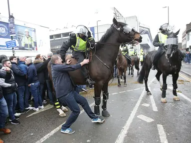  Petugas kepolisian berusaha membubarkan seorang suporter saat terlibat bentrok sebelum pertandingan perempat final Piala FA antara Tottenham Hotspur melawan Millwall di White Hart Lane, London, (12/3). (Yui Mok//PA via AP)