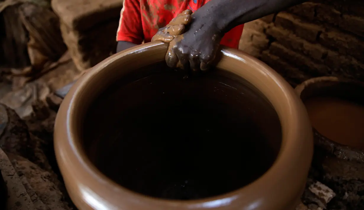 Pekerja membentuk pot tanah liat di sebuah bengkel tembikar di Khartoum, Sudan, Kamis (27/6/2019). Pot tanah liat tersebut nantinya akan dipajang untuk dijual. (AP Photo/Hussein Malla)