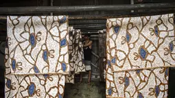 Seorang pekerja menjemur batik di pabrik "batik" kain tradisional Indonesia di Sidoarjo, Jawa Timur (12/11/2019). UNESCO menetapkan batik sebagai karya agung lisan dan warisan budaya takbenda kemanusiaan. (AFP Photo/Juni Kriswanto)
