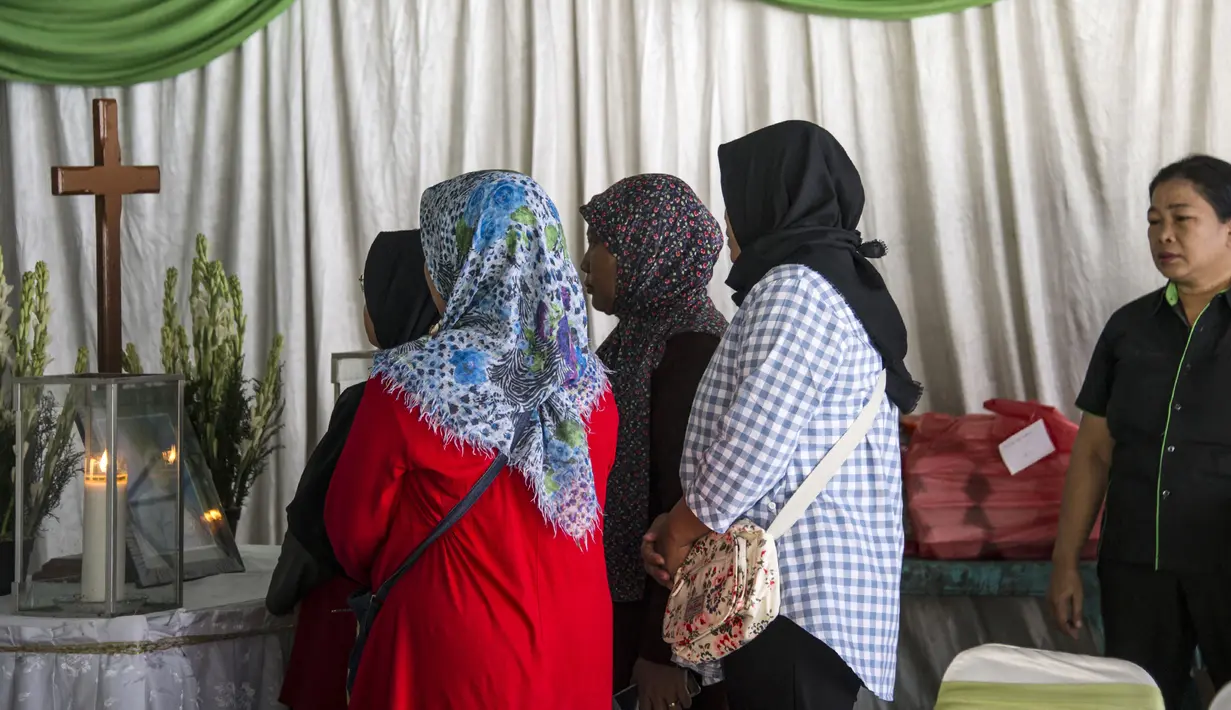 Sejumlah pelayat berdiri di depan peti mati korban bom Surabaya Sri Puji, Surabaya, Jawa Timur, Senin (14/5). Bom bunuh diri menyerang tiga gereja di Surabaya pada Minggu, 13 Mei 2018. (AFP PHOTO/JUNI KRISWANTO)