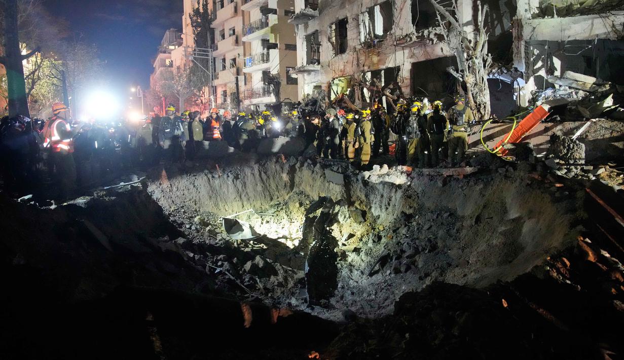 Para petugas dari Komando Pertahanan Dalam Negeri Israel memeriksa reruntuhan gedung apartemen yang rusak akibat serangan rudal Iran, di Tel Aviv, Israel, Minggu 1 Maret 2026 pagi waktu setempat. (AP Photo/Ohad Zwigenberg)