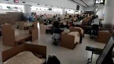Orang-orang menunggu hasil tes virus corona mereka di tempat tidur sementara dari kotak kardus di Bandara Internasional Narita di Narita, dekat Tokyo, 8 April 2020. Bandara tersebut kini dipenuhi dengan bilik-bilik kardus yang berada di area pengambilan bagasi. (Naohiro Katsuta via AP)