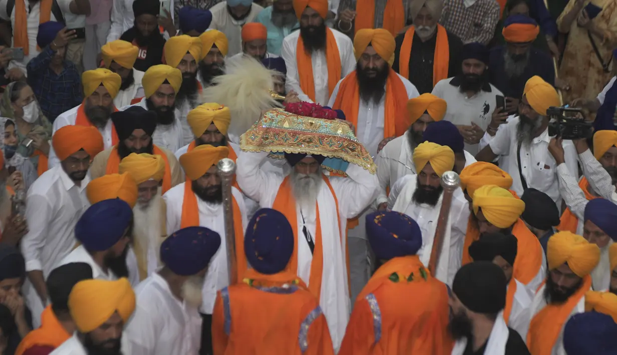 Kepala pendeta Sikh Jagtar Singh (tengah) membawa teks pokok agama Sikhisme, Guru Granth Sahib selama prosesi keagamaan dari Gurudwara Ramsar ke Akal Takht Sahib di Kuil Emas, Amritsar, India, Rabu (19/8/2020). Acara ini untuk memperingati 416 tahun pelantikan Guru Granth Sahib. (NARINDER NANU/AFP)