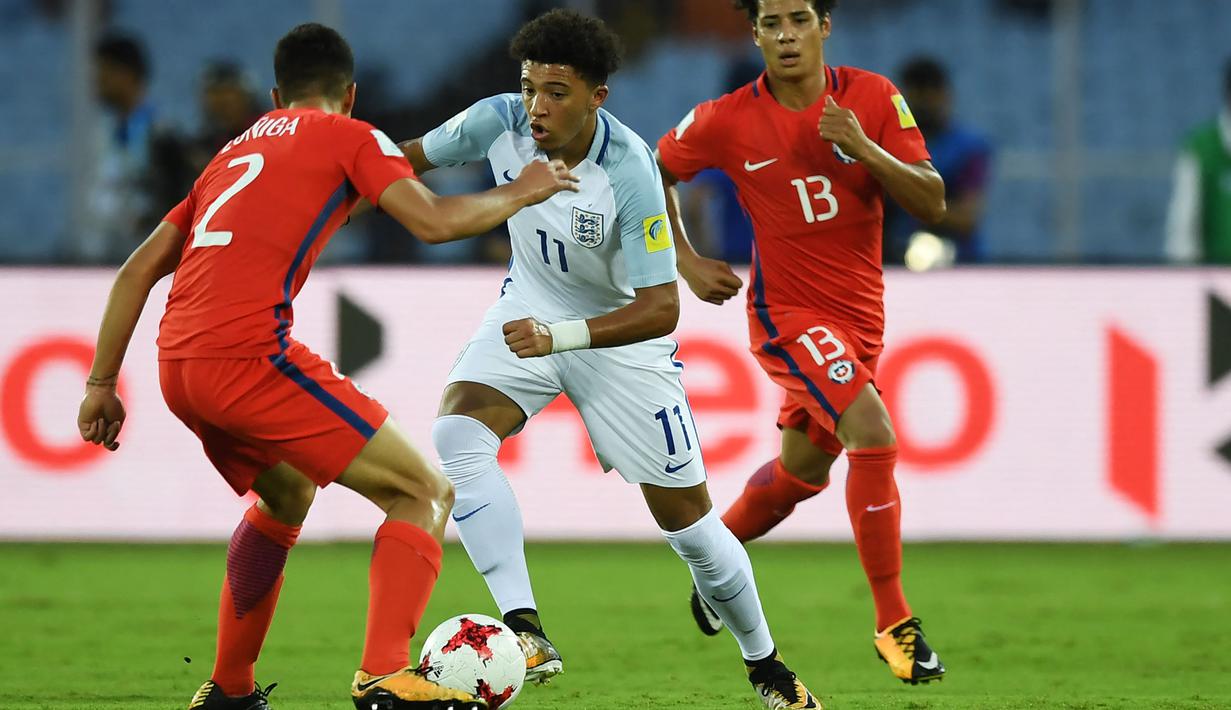 Pemain Timnas Inggris U-17, Jadon Sancho (tengah) berusaha melewati adangan pemain Chile, Gaston Zuniga (kiri) pada laga Grup F Piala Dunia U-17 2017 di Salt Lake Stadium, Kolkata, India, 8 Oktober 2017. Sancho tercatat mencetak 3 gol sepanjang turnamen tersebut. (AFP/Dibyangshu Sarkar)