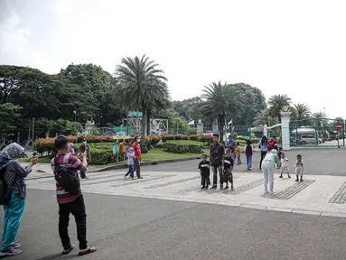 Warga berfoto di halaman luar Monumen Nasional (Monas) Jakarta, Kamis (5/5/2022). Meski kawasan Monas masih ditutup sejak awal pandemi COVID-19 pada Maret 2020 lalu namun tidak menyurutkan minat warga untuk bisa berwisata yaitu dengan memanfaatkan kawasan luar monumen tersebut. (Liputan6.com/Faizal Fanani)