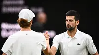 Petenis Serbia Novak Djokovic berjabat tangan setelah menang melawan Jannik Sinner dari Italia dalam pertandingan tenis semifinal tunggal putra Wimbledon 2023 di The All England Lawn Tennis Club, Wimbledon, London, Inggris, Jumat, 14 Juli 2023. (SEBASTIEN BOZON / AFP)