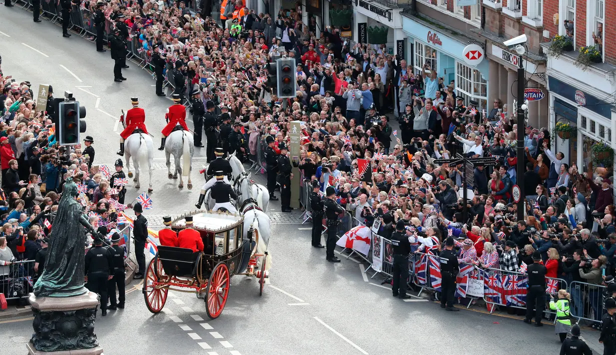 Kerumunan masyarakat menyambut Putri Eugenie dan Jack Brooksbank yang menaiki kereta kencana usai melangsungkan pernikahan di Kapel St. George, Windsor Castle, London, Inggris,  Jumat (12/10). (Andrew Matthews, Pool via AP)