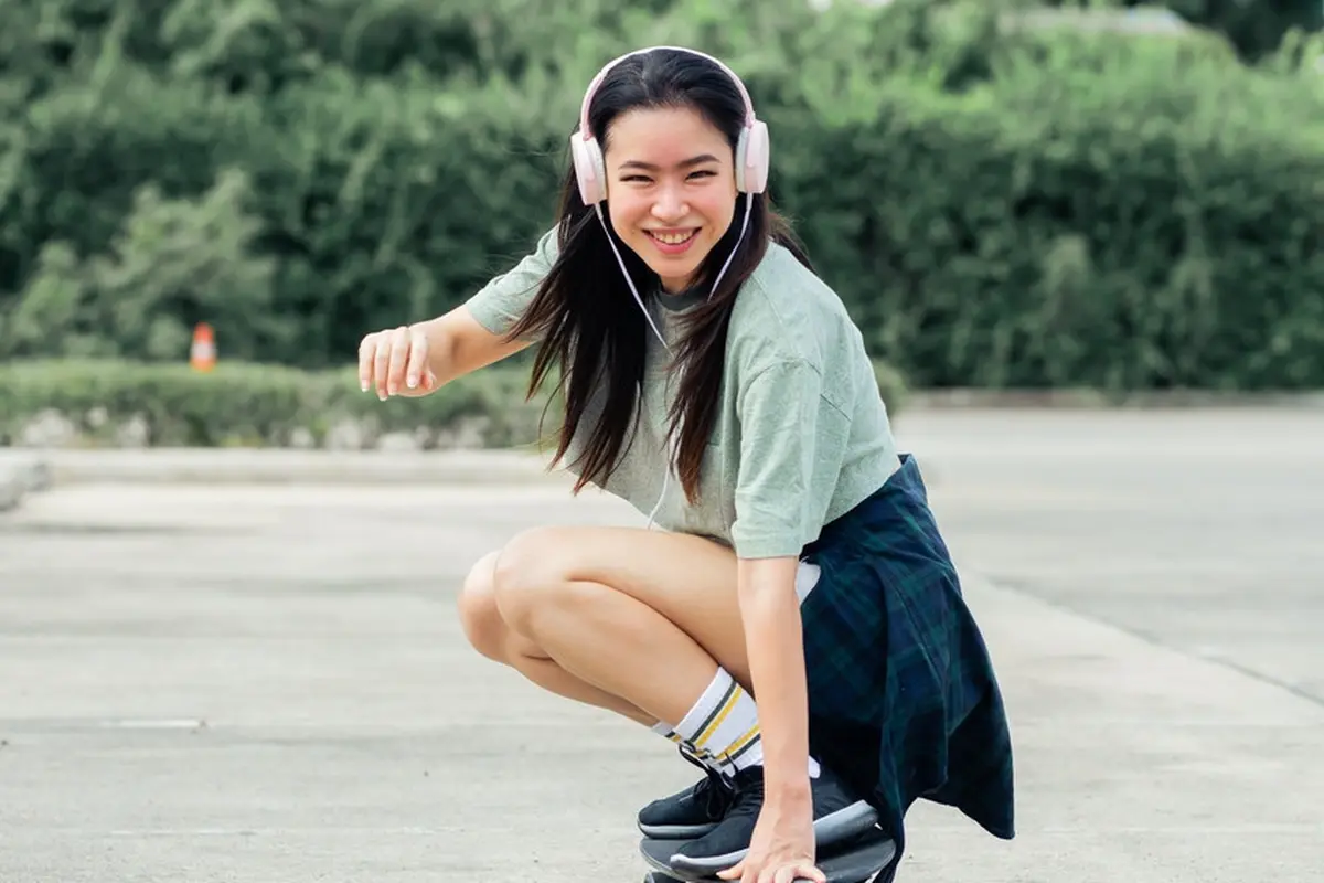 perempuan bahagia main skateboard