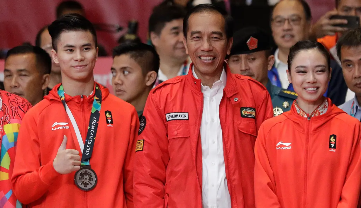 Presiden Joko Widodo foto bersama dengan atlet wushu Indonesia Edgar Marvelo dan Lindswell Lindswell saat menyaksikan pertandingan Wushu di Asian Games ke-18 di Jakarta, (20/8). (AP Photo/Aaron Favila)