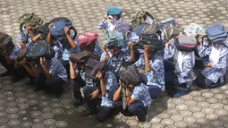 Para murid menggunakan tas untuk pelindung dalam latihan tsunami di Meulaboh (5/9). Sebanyak 24 negara yang berbatasan dengan Samudra Hindia, dari Australia hingga Yaman, mengambil bagian dalam latihan kesiapsiagaan bencana dua tahunan. (AFP Photo/Januar)