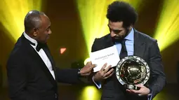 Winger Liverpool, Mohamed Salah menerima penghargaan Pemain Terbaik Afrika 2018 dalam malam penghargaan di Dakar, Senegal, Selasa (8/1). Mohamed Salah mengungguli rekan setimnya, Sadio Mane dan bomber Arsenal, Pierre-Emerick Aubameyang. (SEYLLOU/AFP)