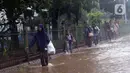 Warga melintasi Jalan Di Panjaitan dekat Halte Transjakarta Cawang Soetoyo yang banjir, Jakarta, Rabu (1/1/2020). Hujan yang mengguyur Jakarta sejak Selasa sore (31/12/2019) mengakibatkan banjir di sejumlah titik di Jakarta. (Liputan6.com/Helmi Fithriansyah)