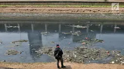 Seorang pria mengamati aliran Kanal Banjir Barat yang berwarna hitam pekat dan dipenuhi tumpukan sampah di Jakarta, Minggu (22/9/2019). Tumpukkan sampah dan aliran air yang berwarna hitam pekat tersebut menimbulkan bau tak sedap. (merdeka.com/Iqbal S Nugroho)