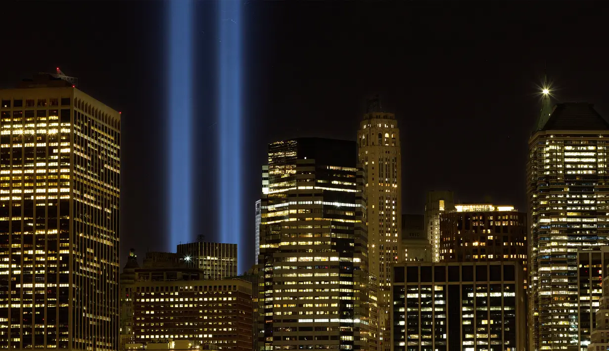 Penampakan sinar biru ‘Tribune in Light’ untuk memperingati serangan 9/11 menyinari Kota New York, Minggu (10/9). Menurut tim khusus investigasi 9/11, sekitar 3.000 korban tewas dalam peristiwa ini. (AP Photo/Mark Lennihan)