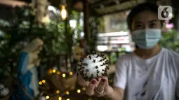 Seorang wanita menunjukkan bola berbentuk virus corona COVID-19 untuk menghias Gereja Theresia di Jakarta, Minggu (20/12/2020). Dekorasi bernuansa pandemi COVID-19 dan kesederhanaan disiapkan untuk memeriahkan perayaan Natal tahun ini. (Liputan6.com/Faizal Fanani)