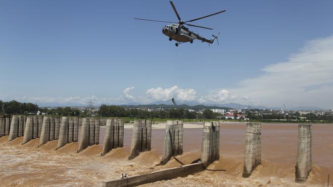 Prajurit Angkatan Udara India turun dari helikopter untuk menyelamatkan para nelayan yang terperangkap dalam banjir di Sungai Tawi di Jammu, India (19/8/2019). Permukaan air di banyak sungai di India utara meningkat setelah hujan lebat di musim hujan. (AP Photo/Channi Anand)