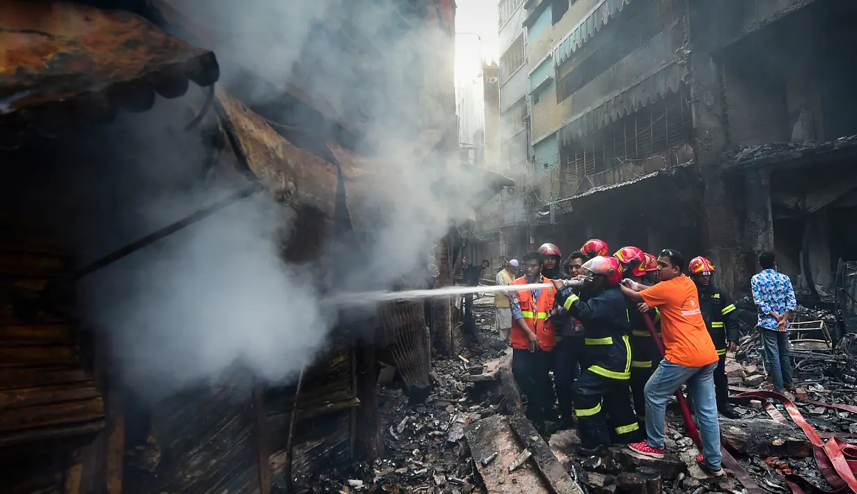 Petugas pemadam kebakaran berusaha memadamkan api setalah api melahap gedung apartemen yang juga digunakan sebagai gudang bahan kimia di Dhaka (21/2). Setidaknya 69 orang tewas dalam kebakaran besar tersebut. (AFP Photo/Munir Uz Zaman)