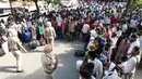 Personel polisi berjaga saat pekerja migran dan keluarga mereja antre menunggu pemeriksaan medis sebelum menaiki kereta untuk kembali ke kota asal mereka ke Jaunpur, negara bagian Uttar Pradesh, setelah pemerintah melonggarkan lockdown di Amritsar, India, Selasa (19/5/2020). (NARINDER NANU/AFP)