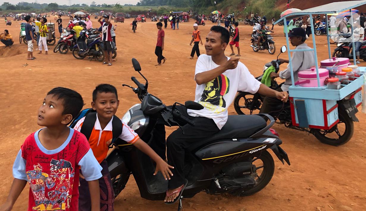 Warga menghabiskan waktu di tanah lapang kawasan Cipayung, Depok, Kamis (11/6/2020). Kurang tegasnya sanksi serta minimnya kesadaran masyarakat akan protokol kesehatan terkait covid-19 menyebabkan kawasan itu menjadi tempat berkerumun warga setiap sore hari. (Liputan6.com/Immanuel Antonius)