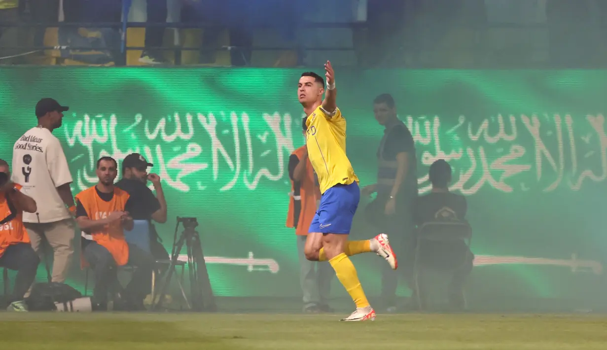 Pemain Al-Nassr, Cristiano Ronaldo merayakan gol pertama timnya ke gawang Al-Ahli pada laga Liga Arab Saudi yang berlangsung di King Saud University Stadium, Riyadh, Arab Saudi, Sabtu (23/09/2023) dini hari WIB. Gol ini dinilai cukup kontroversial karena sisi gawang Al-Ahli yang dijaga oleh Edouard Mendy terlihat tertutup asap yang cukup tebal hasil nyala suar dari para pendukung Al-Nassr. (AFP/Fayez Nureldine)