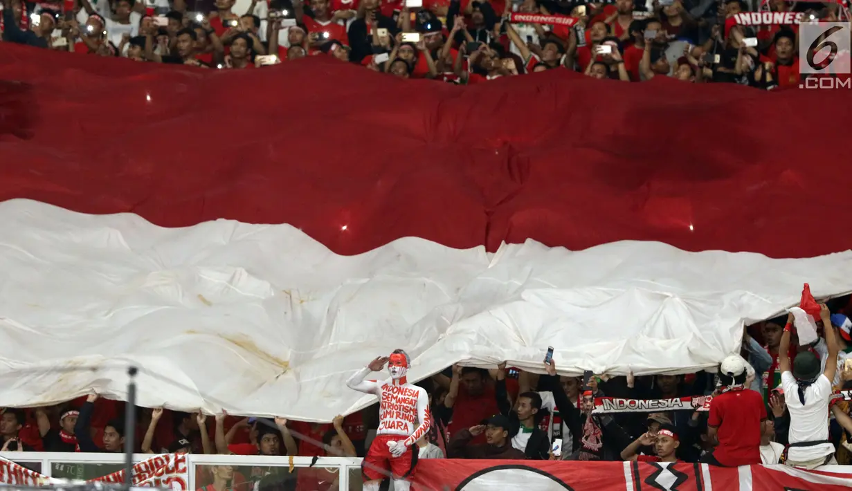 Suporter membentangkan bendera Merah Putih raksasajelang menyaksikan laga Timnas Indonesia U-19 melawan Jepang U-19 pada perempat final Piala AFC U-19 2018 di Stadion GBK, Jakarta, Minggu (28/10). Indonesia kalah 0-2. (Liputan6.com/Helmi Fithriansyah)