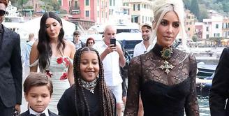 Kim Kardashian tampil nyentrik di hari pernikahan kakaknya itu. Perempuan 41 tahun itu tampil bergaya gothic mengenakan lace dress warna hitam. Gayanya disempurnakan dengan bros dan kalung choker, serta tata rambut high bun. (Instagram/enews).