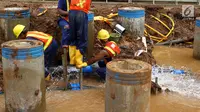 Petugas memperbaiki saluran pipa air bersih milik PAM Jaya yang bocor di kawasan proyek Jalan Layang Tol Becakayu, Jakarta, Jumat (15/12). (Liputan6.com/JohanTallo)