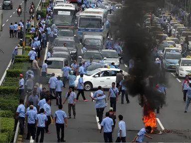 Sejumlah sopir taksi yang melakukan demo membakar ban dan memblokir jalan di tol dalam kota, Mampang, Jakarta, Selasa (22/3). Terlihat asap membumbung tinggi dari ban yang terbakar. (Liputan6.com/Johan Tallo)