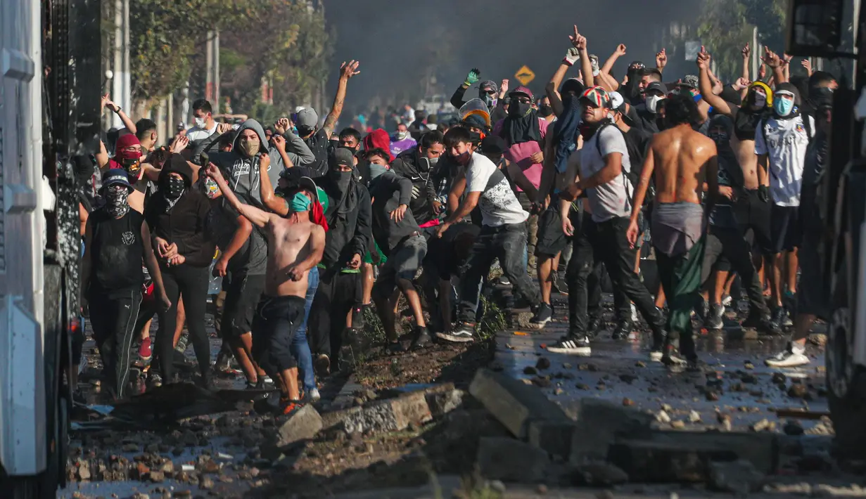 Demonstran saat bentrok dengan polisi di tengah pandemi virus corona Covid-19 selama penguncian wilayah (lockdown) di lingkungan miskin di Santiago, Chili, (18/5/2020). Mereka  protes menuntut bantuan makanan dari pemerintah. (AP Photo/Esteban Felix)
