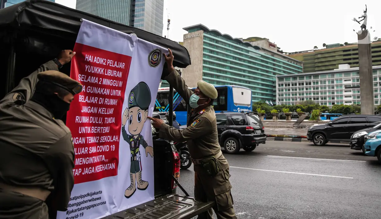 Petugas Satpol PP memasang spanduk mini untuk memberikan imbauan sekaligus sosialisasi kepada masyarakat guna mencegah penularan Covid-19 di Bundaran HI, Jakarta, Kamis (19/3/2020). (Liputan6.com/Faizal Fanani)