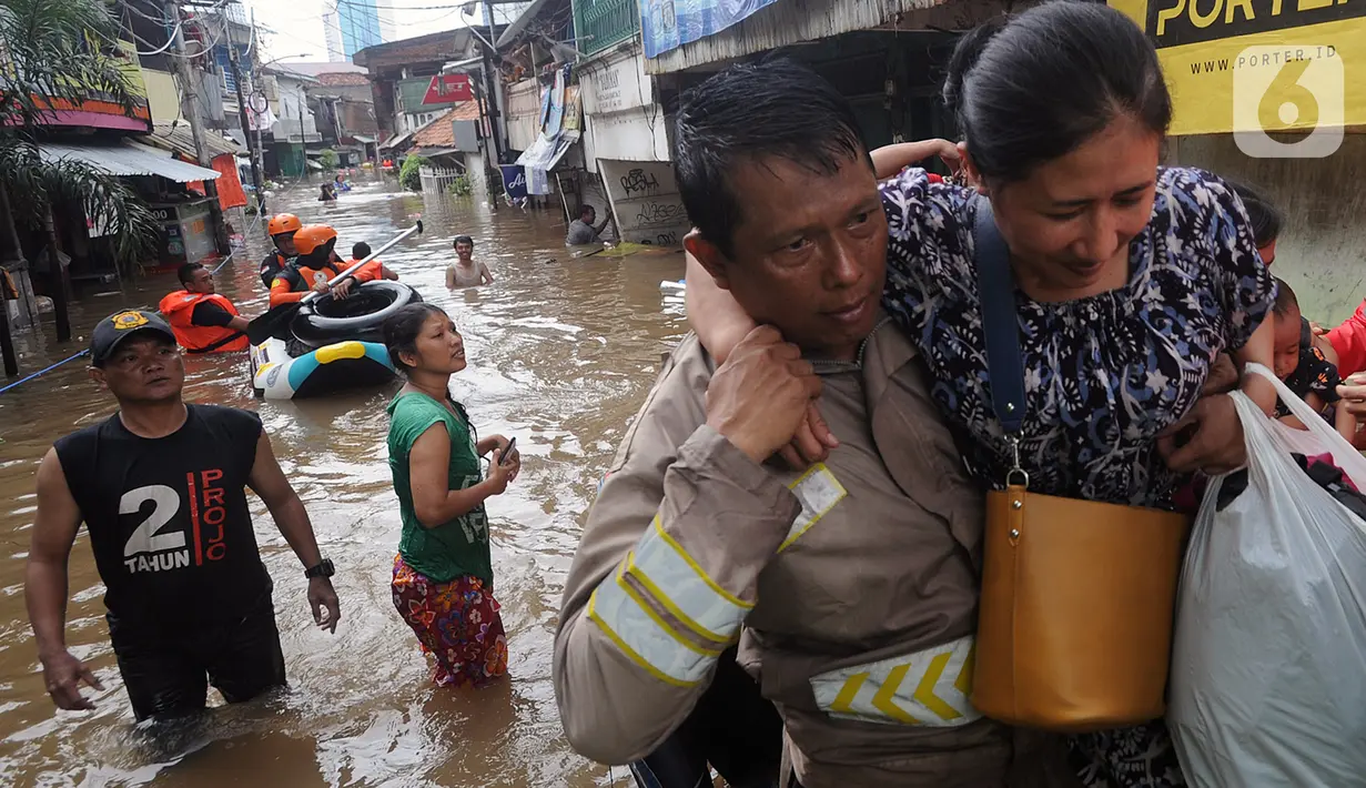 Petugas mengevakuasi warga korban banjir di kawasan Karet Pasar Baru Barat, Jakarta, Selasa (25/2/2020). Banjir yang terjadi sejak subuh akibat luapan Kanal Banjir Barat tersebut merendam ratusan rumah hingga setinggi dua meter. (merdeka.com/Arie Basuki)