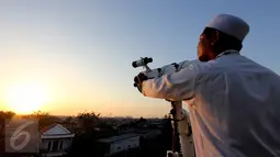 Seorang anggota tim Rukyatul Hilal gabungan meneropong posisi hilal di atas Mesjid Al Musriyiin, Jakarta, Kamis (16/7/2015). Berdasarkan data astronomis ketinggian hilal saat matahari terbenam sekitar tiga derajat. (Liputan6.com/Helmi Afandi)