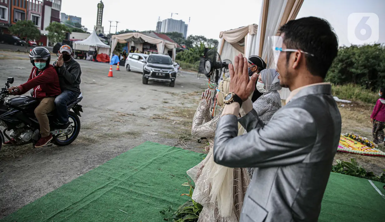 Pasangan mempelai bersama keluarga saat menyapa tamu undangan pada acara resepsi pernikahan secara "drive thru" di Bekasi, Jawa Barat, Sabtu (8/8/2020). Resepsi pernikahan secara drive thru menjadi alternatif pesta pernikahan guna mencegah penyebaran wabah COVID-19. (Liputan6.com/Faizal Fanani)
