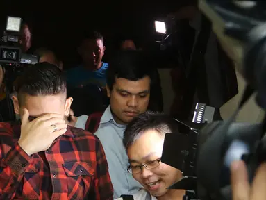 Aktor dan presenter Ganindra Bimo menutup mukanya saat para wartawan menghampirinya usai menjalani pemeriksaan di polsek Jagakarsa, Jakarta, Kamis (18/02/2016) .(Liputan6.com/Herman Zakharia)