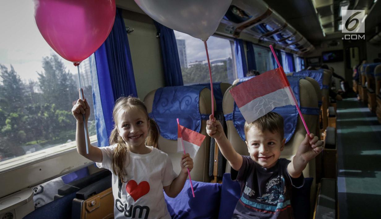 Warga negara asing mengibarkan bendera merah putih di Stasiun Gambir, Jakarta, Kamis (1/6). Dalam rangka memperingati HUT Pancasila PT KAI Daop 1 memberikan pin dan bendera merah putih kepada penumpang kereta api. (Liputan6.com/Faizal Fanani)