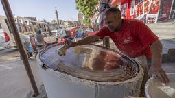 Pembuat penganan Mesir Mostafa Anwar membuat makanan penutup tradisional yang disebut "Kunafa" pada bulan Ramadhan, di kiosnya di ibu kota Kairo, 14 April 2022.  Kunafa terbuat dari adonan pastry mirip bihun, kemudian diisi dengan isian kacang, lalu dipanggang. (Khaled DESOUKI/AFP)