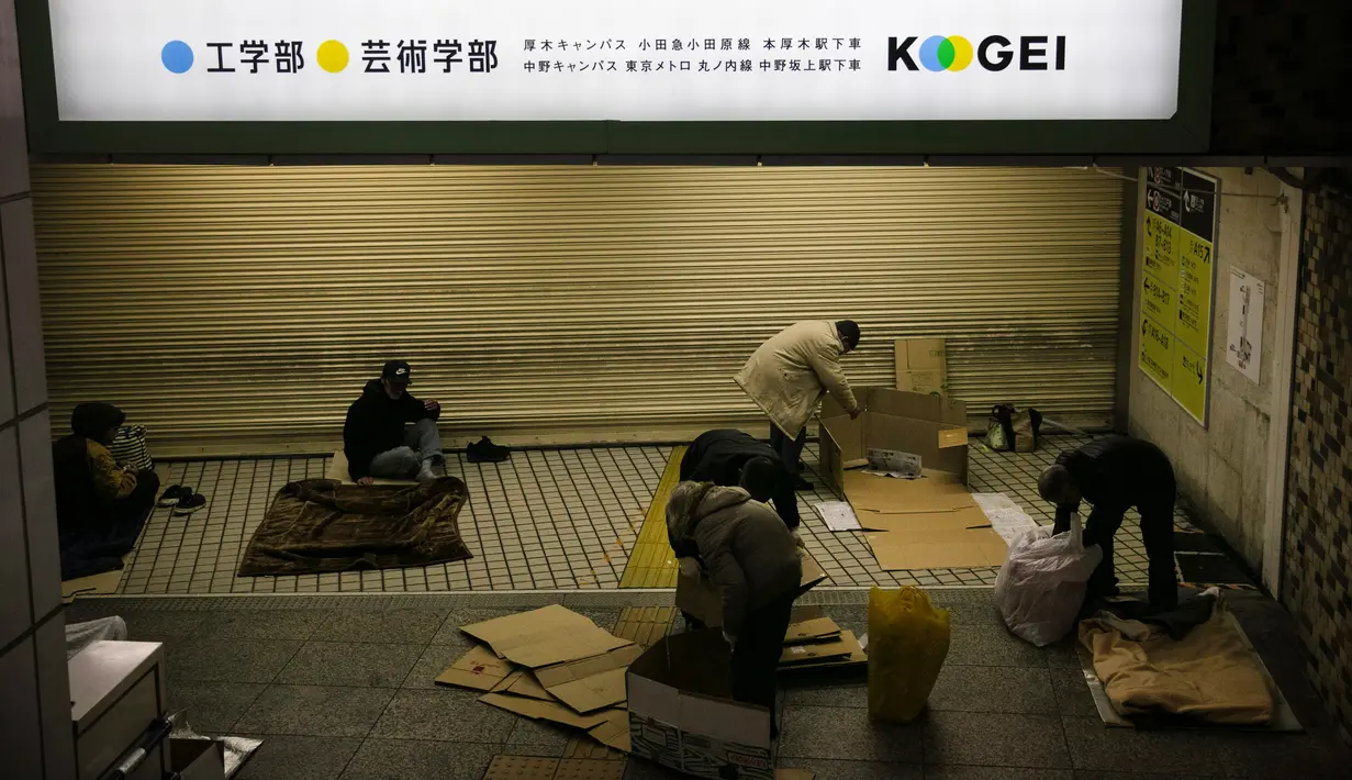 Sejumlah tunawisma mempersiapkan diri untuk tidur di Stasiun Shinjuku, Tokyo, Jepang, Rabu (15/1/2020). Puluhan tunawisma tidur nyenyak di stasiun kereta bawah tanah Tokyo. (AP Photo/Jae C. Hong)