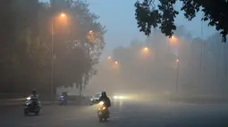 Warga India memacu kendaraannya melintasi jalan di New Delhi, India yang tertutup kabut asap akibat polusi udara, Rabu (8/11). Asosiasi Medis India mengumumkan kondisi darurat kesehatan setelah kabut asap tebal menutupi kota tersebut. (SAJJAD HUSSAIN/AFP)