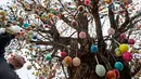 Uwe Gerstenberg mendekorasi pohon robinia dengan 10.000 telur paskah warna-warni di kota Saalfeld, Jerman, Jumat (30/3). Pohon Paskah merupakan tradisi lain yang berumur berabad-abad dan dibuat dari pohon atau semak kecil yang masih hidup. (AP/Jens Meyer)