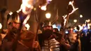 Peserta melakukan pawai sambil membawa obor dalam perayaan Bonfire Night melintasi jalan di Sussex Timur, Inggris, Selasa (5/11/2019). Obor yang mereka bawa itu nantinya akan digunakan untuk menyalakan kembang api dan api unggun. (Ben STANSALL/AFP)