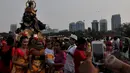 Sejumlah warga berfoto di dekat boneka raksasa saat pawai Ogoh-ogoh di kawasan Monas, Jakarta, Jumat (20/3/2015). Pawai tersebut merupakan rangkaian dari prosesi menjelang Hari raya Nyepi Tahun Saka 1937. (Liputan6.com/Johan Tallo) 
