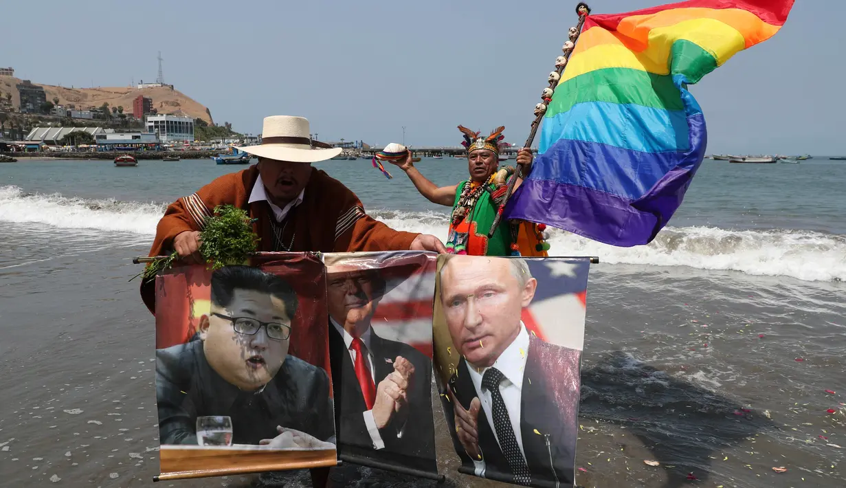 Dukun Peru memegang poster Presiden AS Donald Trump, Pemimpin Korea Utara Kim Jong-un dan Presiden Rusia, Vladimir Putin selama ritual untuk menyambut tahun baru  di pantai Agua Dulce, Lima, Kamis (27/12). (AP/Martin Mejia)