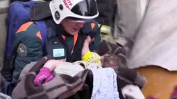Tim penyelamat menggendong seorang bayi yang ditemukan selamat setelah tertimbun reruntuhan gedung apartemen yang ambruk di Magnitogorsk, Rusia, Selasa (1/1). Bangunan itu porak poranda akibat ledakan gas (Russian Ministry for Emergency Situations via AP)
