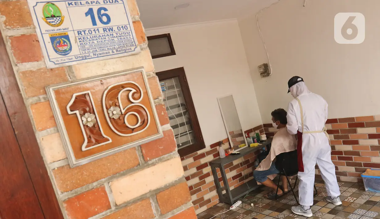 Tukang cukur mengenakan APD saat memotong rambut di halaman rumah pelanggan, Kelapa Dua, Depok, Jawa Barat, Senin (27/4/2020). Penerapan PSBB Kota Depok membuat tukang cukur tersebut menerima jasa panggilan ke rumah dan mengenakan APD untuk mencegah penularan COVID-19. (Liputan6.com/Herman Zakharia)