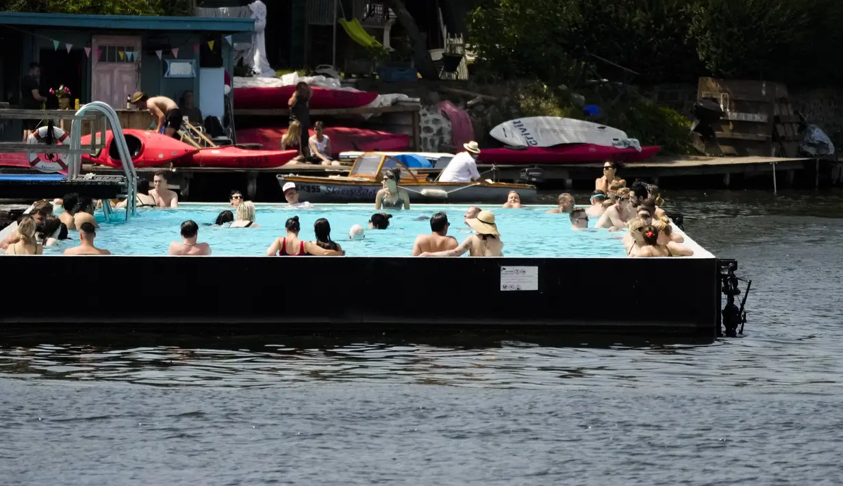 Orang-orang menikmati hari musim panas di kolam yang disebut Badeschiff, Bathing Ship, di Berlin, Minggu (19/6/2022). Di Jerman, di mana suhu tertinggi diperkirakan 38 derajat celcius (100,4 F), menteri kesehatan mendesak kelompok rentan menjaga tubuh tetap terhidrasi. (AP Photo/Markus Schreiber)