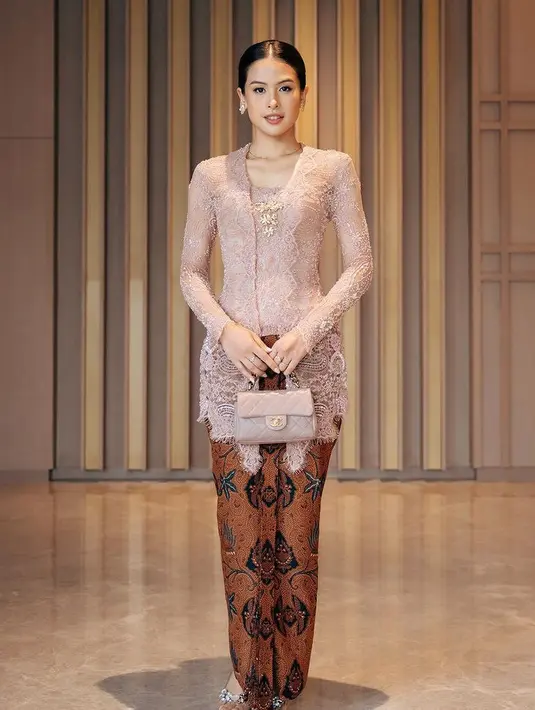 Maudy juga tampil dengan kebaya warna pink brokat lengan panjang, serasi dengan tas Chanelnya. Dipadukan kain batik lilit sebagai bawahan. [@maudyayunda]